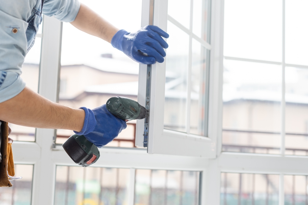 homme &agrave; main r&eacute;glant la fen&ecirc;tre en plastique blanc pvc &agrave; l'int&eacute;rieur. ouvrier utilisant tournevis pour r&eacute;parer la fen&ecirc;tre upvc. entretien des devoirs